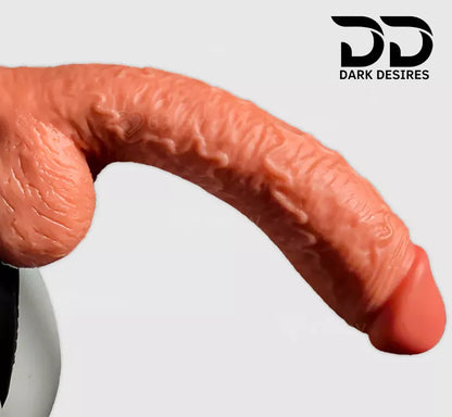 A close angle realistic skin-toned dildo with textured detailing and a flared base A realistic textured dildo with a black harness-style strap, 10-inch curved Extra Thick strap-on dildo with suction cup and adjustable harness for G-spot, vaginal and anal play Black faux harness leather belt Sex Toys for Women in Mumbai India by DarkDesires